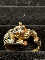 Close up photo of vintage 18K gold leopard ring with rhinestone embellishments on textured ring box.