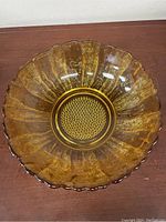 Top-down view of amber sunflower glass bowl showing the scalloped edge and textured petals radiating from a patterned center.
