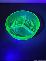 Top view of the vintage 3-section divided Vaseline uranium glass dish glowing under UV light.
