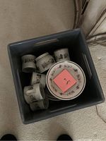 Top view of a plastic container holding assorted Royal Doulton dishes with Harvest Garland floral pattern, including cups, bowls, and plates.