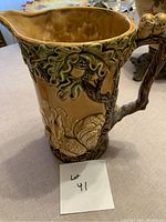 Image of jug showing oak leaf, acorn design and squirrel on handle.