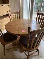 Photo showing 37.5-inch round oak table with five matching oak chairs with brown seat cushions placed around the table.