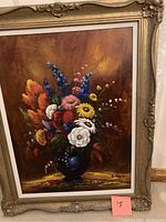 Framed oil painting showing a detailed bouquet of flowers in a vase with a warm brown background.