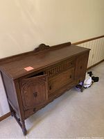 Front view of 54-inch carved oak sideboard, left cabinet door open to show interior shelf