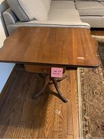 Top view showing wooden drop-leaf table top with scalloped edges and surface scratches.