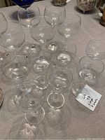 Photo showing all 13 wine glasses, 6 large and 7 small, arranged on a tablecloth with a note indicating 6 large and 7 small glasses.
