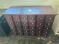 Front view of the entire wooden cabinet showing all 30 numbered drawers and finish.