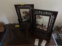 Overview of two carved hardwood frames and matching folding book stand on tabletop