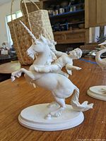 Front three-quarter view showing unicorn rearing with Cupid figure on its back