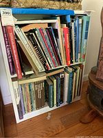 Two white shelves holding the books from front view showing the range and titles present.