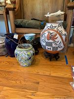 Four vases arranged on wood floor: cobalt blue vase, multicolor ginger jar, palm tree planter, large Acoma Pueblo jar on stand