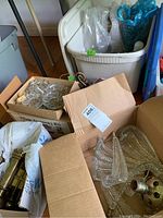Wide view of boxes containing assorted glass prisms, lamp parts, and hardware including plastic bags and packing materials.