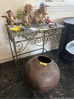 Ornate metal plant stand with felted wool animals displayed on top