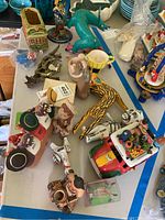 Overall view of assorted figurines and pottery including animals and cultural figures arranged on a table.