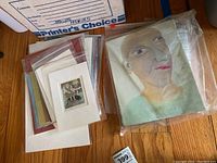 Overview of all unframed matted prints and one canvas painting laid out on floor