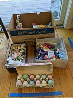 Multiple boxes containing various Easter themed items including bunny figurines, toys, and eggs.