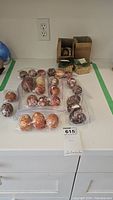 Photo showing multiple hand painted Ukrainian Easter eggs displayed on a counter in small groups including ziplock bags and small containers.