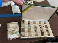 Open green velvet box showing neatly arranged stones in labeled compartments with gemstone names.