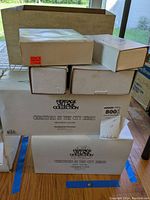 Stack of six Heritage Village Collection boxes including Christmas in the City series items with one large box at bottom and smaller boxes above