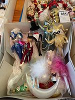 Box of assorted vintage glass Christmas ornaments showing various figures including policemen, ballerinas, and a jester with feathers and hats.