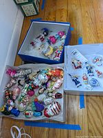 Three boxes containing assorted glass and porcelain Christmas ornaments with various figures and styles.