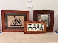 Three framed silhouette art pieces displayed together, showing varied frames and black silhouette imagery under glass.
