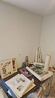 Overview photo of the collection showing multiple vintage unframed prints, some rolled and some flat on a table with varied sizes and visible soiling.