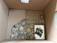 Overhead view of box containing filigree jewelry pieces and enamel landscape pendant in small box