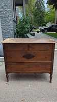 Front view of antique wooden dresser showing the four drawers, drawer pulls, keyholes, and worn top surface.