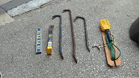 Wide shot of all tools laid on pavement showing pry bars, levels, and electrical tester