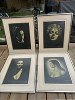 Image showing the full set of four framed black and white portraits by J. Craig Hille Toncareva on a wooden surface outdoors.