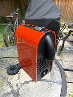 Side angle showing orange coffee machine body and missing water container.