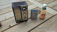 Photo showing the two vintage radios side by side on a wooden surface including a glass bottle for scale.