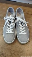 Top-down view of the pair of light grey knit fabric casual shoes with white laces.