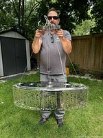 Man holding oval pendant light fixture outdoors showing size and detail
