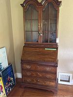 Full exterior view of wooden secretary desk and hutch showing bonnet top and lower drawers