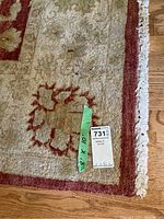 Close-up of corner showing floral pattern, beige border, fringe, and lot tag with measurements