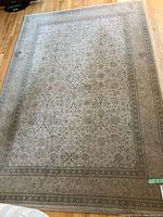 Full view of the rectangular grey toned area rug with detailed floral pattern. Surface shows some worn and stained areas.