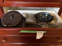 Drawer containing a black speckled roasting pot, muffin tins, bundt pan, rectangular baking pans, and trivets