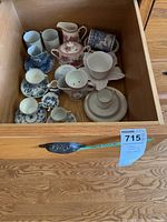 Drawer containing assorted teacups, saucers, creamers, and sugar bowls in various floral and decorative patterns.