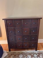 Front view of dark wood dresser showing 16 square drawers arranged in a 4×4 grid