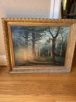 Full view of the framed landscape painting with forest setting and figure.