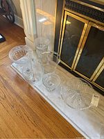 Crystal vase, matching bowl, two glass ice buckets, cake dish, and salt and pepper shakers displayed on a marble hearth in front of fireplace.