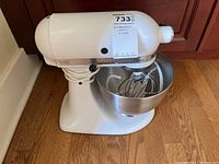 Front view of white mixer with bowl and whisk attached