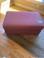 Front view of the large rust-colored ottoman on a patterned area rug