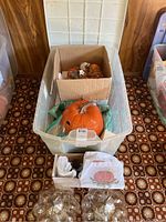 Overview of plastic storage bin holding a large ceramic pumpkin, box with smaller pumpkin jar, and bags with additional items.