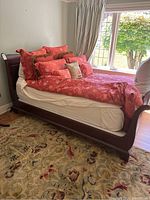 Side view of assembled queen size sleigh bed with mattress and bedding