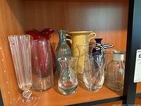 All vases arranged on wooden shelf showing variety in color, size, and shape