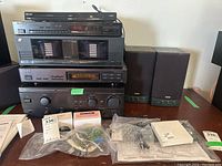 Overall view of stacked audio components including Philips DVD players, a large stereo cassette deck, amplifier, and RCA speakers on the right, with various cables and small boxes in front.
