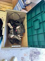Top-down view inside open plastic bin showing various power tools and cords packed inside.